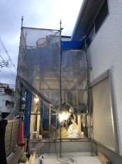 雨が降ってきたのでブルーシートで養生して木材が濡れるのを防いでいます。